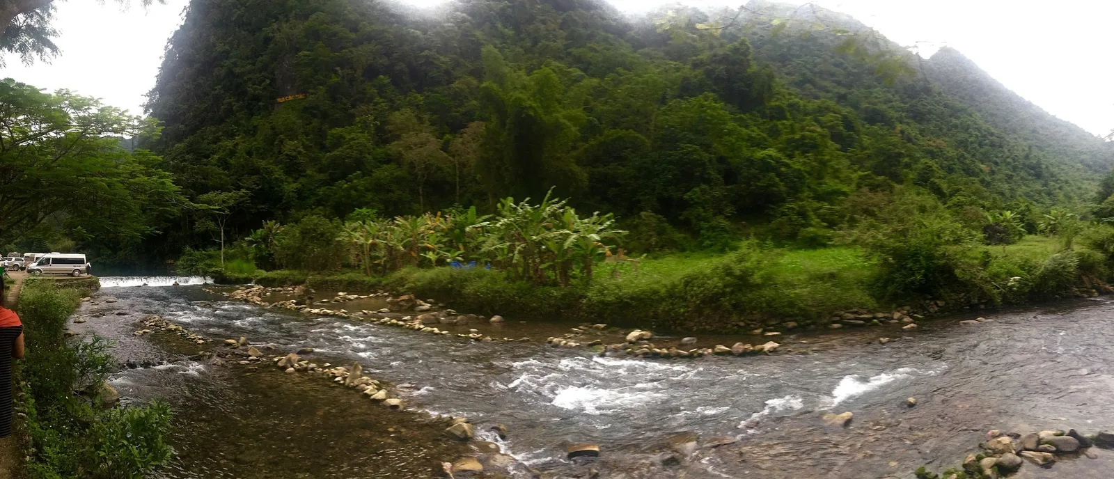 Dòng suối đá uốn quanh thung lũng xanh dưới chân núi phủ sương ở Cao Bằng, Việt Nam.
