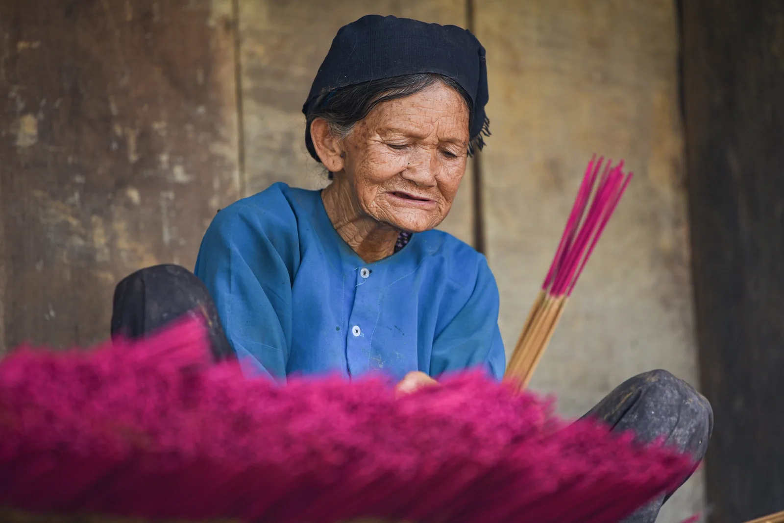Một cụ bà mặc trang phục truyền thống làm hương que màu hồng bằng tay gần Cao Bằng.