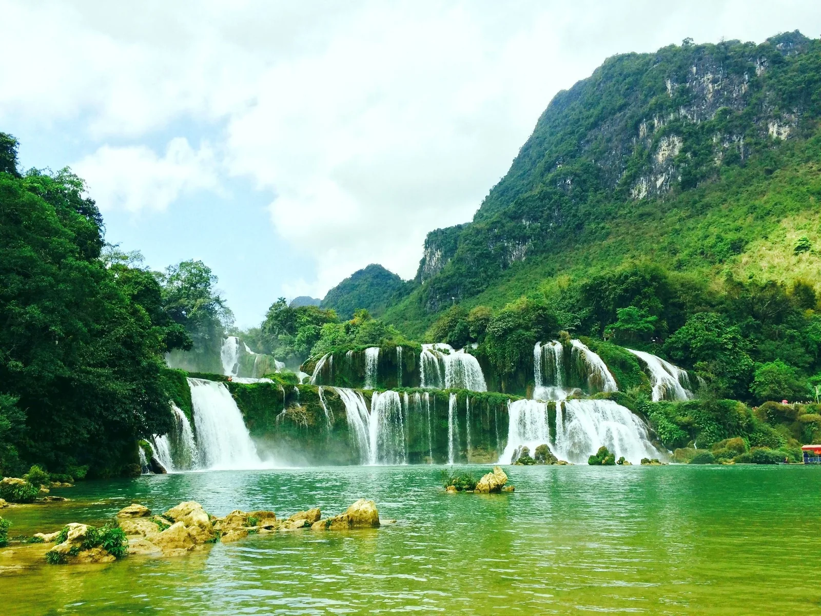 Thác Bản Giốc đổ xuống các tầng đá vôi vào dòng sông xanh ngọc dưới chân núi đá vôi ở Cao Bằng.