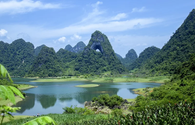 Một vòm đá tự nhiên xuyên qua ngọn núi đá vôi phía trên hồ nước yên bình ở Cao Bằng.